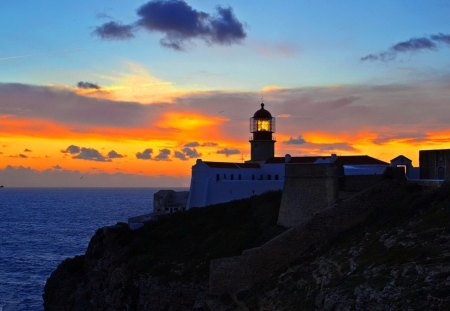 Lighthouse - lighthouse, houses, mountain, sunset, blue sea, red sky, clouds, roks, birds