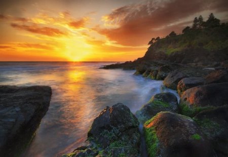 Sunset on the Ocean - sky, day, sun, shore, sunset, nature, yellow, reflection, smooth, clouds, rock