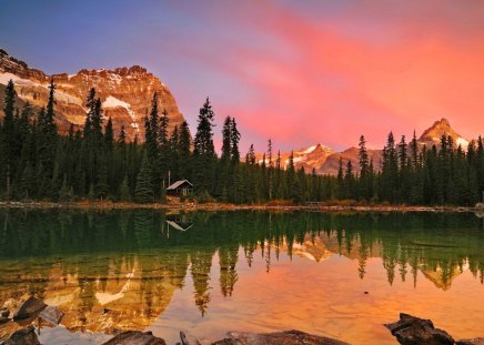 House on lakeshore - cottage, sky, sundown, trees, rocks, reflection, clouds, sumset, orange, afternoon, morning, lake, mountain, summer, shore, peaks, glow, nature, red, stones, cabin, sunrise