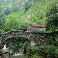 stone bridge and cabin on mountain stream