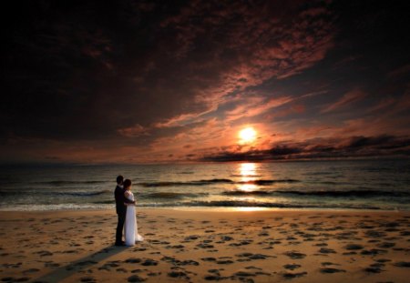 Watching The Sunset - female, beach, splendor, man, reflection, sand, ocean waves, hug, sky, clouds, sunlight, bride, beautiful, wedding, girl, sea, beauty, colors, lovely, love, ocean, nature, sunset, lady, woman, waves, peaceful