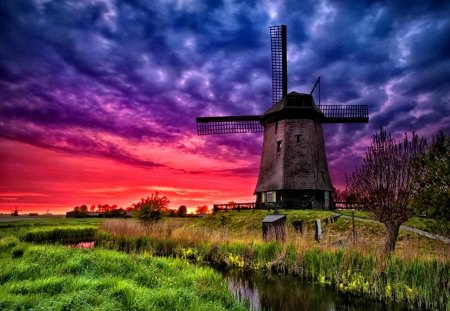 Windmill at sunset - nice, sky, sundown, trees, water, stream, sunset, creek, purple, river, clouds, green, grass, mill, lovely, nature, beautiful, windmill