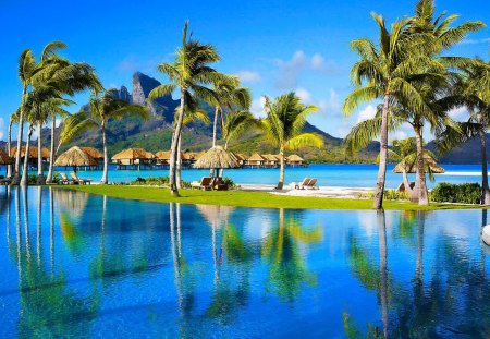 A tropical place - nice, hut, sky, beach, tropics, bungalows, clear, mirrored, wind, crystal, reflection, clouds, holiday, resort, relax, palm trees, palms, tropical, shore, place, cabins, lovely, exotic, nature, blue, beautiful, rest, waters, breeze, destination