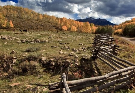 rugged fence around a pasture - road, hills, fence, pasture