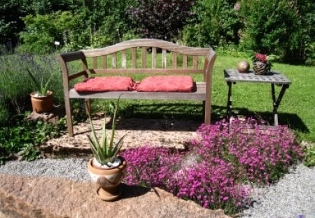 Relaxing place in the garden - sofa, table, pillows, flowers, stones, grass, garden