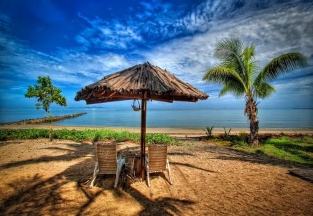 A place in paradise - nice, sky, beach, tropics, straw, paradise, water, vacation, view, clouds, umbrella, holiday, sunny, grass, relax, sit, rays, sands, ocean, palm tree, palms, summer, tropical, shore, lovely, exotic, nature, pier, beautiful, rest, sea