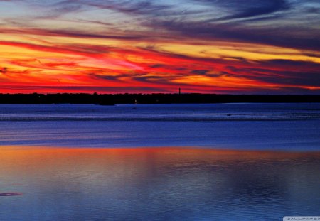 splash of colors at sunset - red sunset, clouds, blue sea, black shore