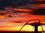 airplane landing in front of a sunset