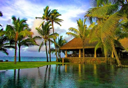 Tropical bungalows - beach, grass, shore, bungalow, palm trees, nice, emerald, sky, palms, water, beautiful, mirrored, sea, lovely, ocean, nature, pool