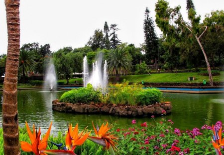 Fountain in park - nice, sky, trees, greenery, water, colorful, pleasant, fountain, pretty, reflection, walk, green, grass, garden, pond, relax, fresh, lake, park, palms, lovely, nature, beautiful, rest, flowers