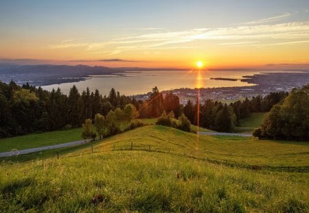 Peaceful Place - sunrise, sunrays, path, field, hill, sunlight, house, road, beauty, colors, valley, village, nature, sunset, green, horizon, hills, splendor, landscape, grass, reflection, view, pathway, houses, sky, sun, clouds, trees, water, beautiful, lovely, tree, rays, peaceful