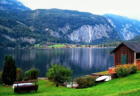 Lakeshore houses - pretty, summer, cabin, grass, reflection, mountain, countryside, shore, riverbank, cliffs, lake, nice, houses, cottage, sky, clouds, greenery, trees, water, beautiful, lovely, lakeshore, village, slopes, river, nature, green