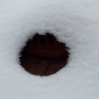 a round hole molten in the snow on the roof