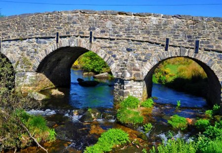 Stone bridge over blue river - nice, sky, greenery, stream, water, summer, lovely, creek, bushes, nature, blue, beautiful, river, stones, bridge