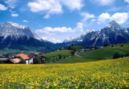 spring alpine landscape in france - village, meadows, mountains, clouds