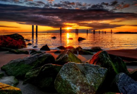 Sticks and stones - nice, sky, sunshine, beach, sundown, water, colorful, sunset, rocks, amazing, pretty, reflection, clouds, sticks, rays, ocean, sunlight, shore, lovely, nature, glow, beautiful, stones, colors, sunrise, sea