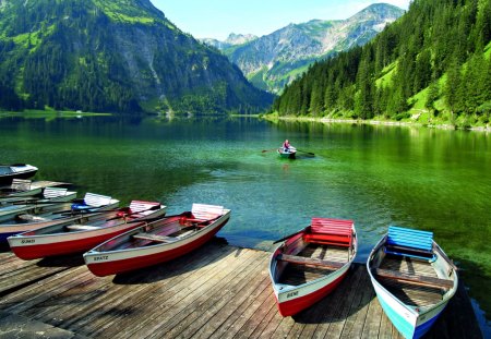 Boats on the pier - pretty, summer, grass, reflection, crystal, mountain, shore, riverbank, cliffs, lake, nice, canoe, water, beautiful, mirrored, lovely, dock, peaks, lakeshore, slopes, boats, colorful, river, wooden, nature, green, clear