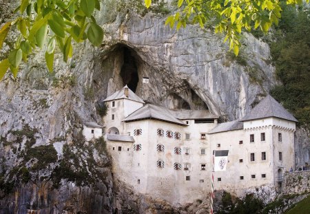 predjama castle slovenia - cliff, cave, trees, castle