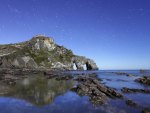 star showers above a rocky sea coast