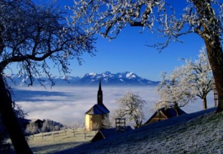 Winter view - pretty, blue, cabin, snow, church, mountain, sight, view, barn, mist, cittage, nice, farm, cloudy, sky, clouds, house, branches, trees, winter, beautiful, lovely, peaks, village, slopes, nature, bright