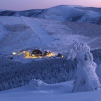 On a mountain top with a hotel with lights  in the distance