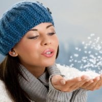 Girl blows away the snow from the palms