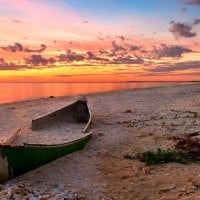 sunset on a broken canoe on a beach