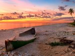 sunset on a broken canoe on a beach