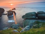 sunlight coming through arched rocks in seacoast