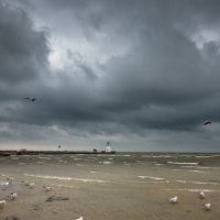 lighthouse on a pier under stormy clouds