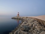 lighthouse on a rock pier at a misty sea