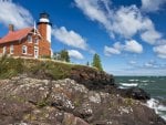 red brick lighthouse on a cliff overlooking the sea