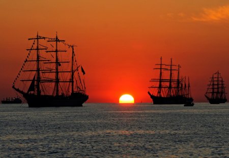 tall ships at sea in sunset