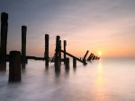 sunrise over an old pier in a misty sea