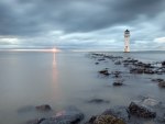 lighthouse off the beach at sunset