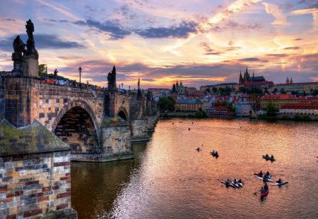 boat racing on a river in prague at sundown - clouds, boats, river, sundown, spectators, city, bridge