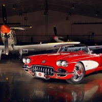 vintage corvette in a hanger with WWII fighters