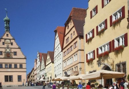 Rothenburg ob der Tauber - window shutters, flower boxes, people, clock, steeple, blue sky