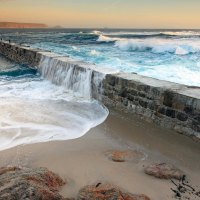 waves crashing over seawall