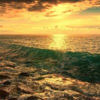 waves on a rocky shore under golden sky