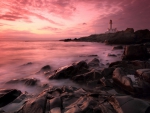 fantastic pink sunset over lighthouse on rocky shore