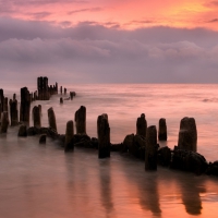 broken pier in a beautiful peach colored sea and sky