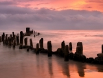 broken pier in a beautiful peach colored sea and sky