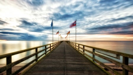 flags flapping on a wonderful sea pier - clouds, wind, sunset, flags, sea, pier