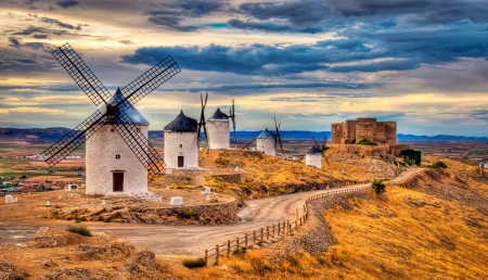 Sunset at the Windmills - hills, roads, white, evening, yellow, clouds, blue, skies, dusk, grass