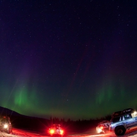expedition trucks under northern light in fish eye