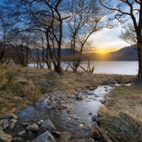 creek flowing into lake at sunset