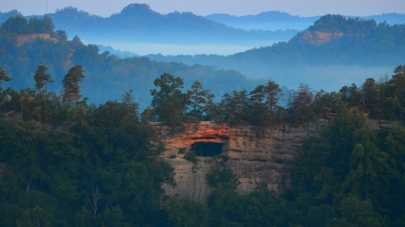 natural window in a cliff surrounded by a forest - fog, cliff, portal, forest, mountains