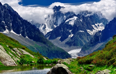 In the foot of snowy mountain - pretty, quiet, hills, summer, creek, stream, grass, mountain, flowers, foot, shore, cliffs, nice, place, sky, clouds, beautiful, snowy, slope, lovely, valley, peaks, stones, river, nature, serenity, rocks