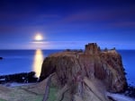 moon over castle ruins on a coastal cliff